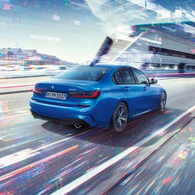 BMW 3 Series Sedan,側面后視圖 BMW 3 Series Sedan 後部四分之三角度影像,位於白天城市背景前。