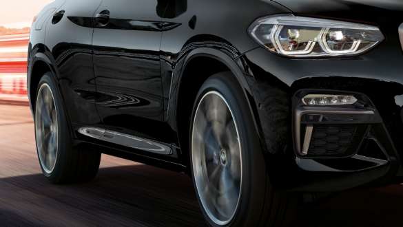 BMW X4 M40i 和 BMW X4 M40d,四分之三側面視圖。 BMW X4 M40i 和 BMW X4 M40d,藍寶石黑金屬,行駛,外觀,輕合金輪圈不斷旋轉的四分之三側面視圖。