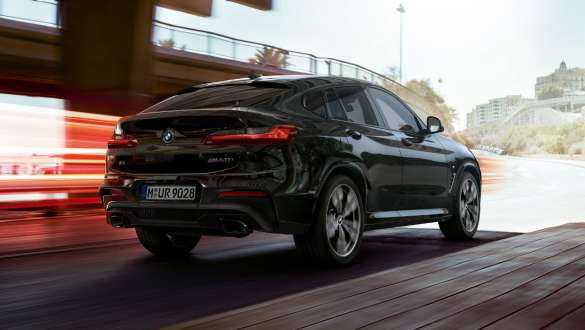 BMW X4 M40i 和 BMW X4 M40d,四分之三尾部視圖。 BMW X4 M40i 和 BMW X4 M40d,藍寶石黑金屬,行駛中,外觀設計,四分之三尾部視圖,帶燈條。