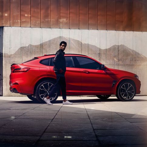 BMW X4 M Competition,側面視圖與年輕人。 BMW X4 M Competition,Toronto Red 金屬,外觀設計,側面視圖與年輕人。