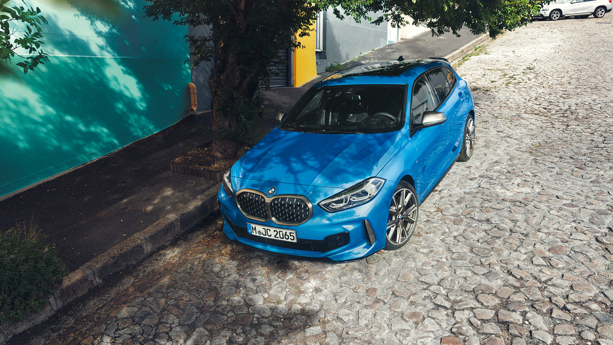 路邊的 1 Series BMW。 1 Series BMW,Misano Blue 金屬,四分之三正面視圖,停在路邊,俯視圖。