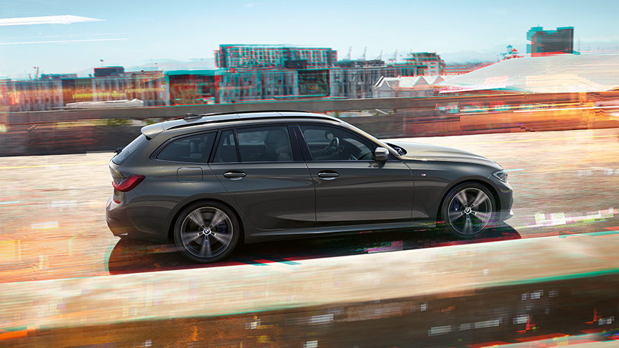 BMW 3 Series Touring,行駛在街道上,側面拍攝視圖  BMW 3 Series Touring,行駛在城市背景前的街道上,側面拍攝視圖