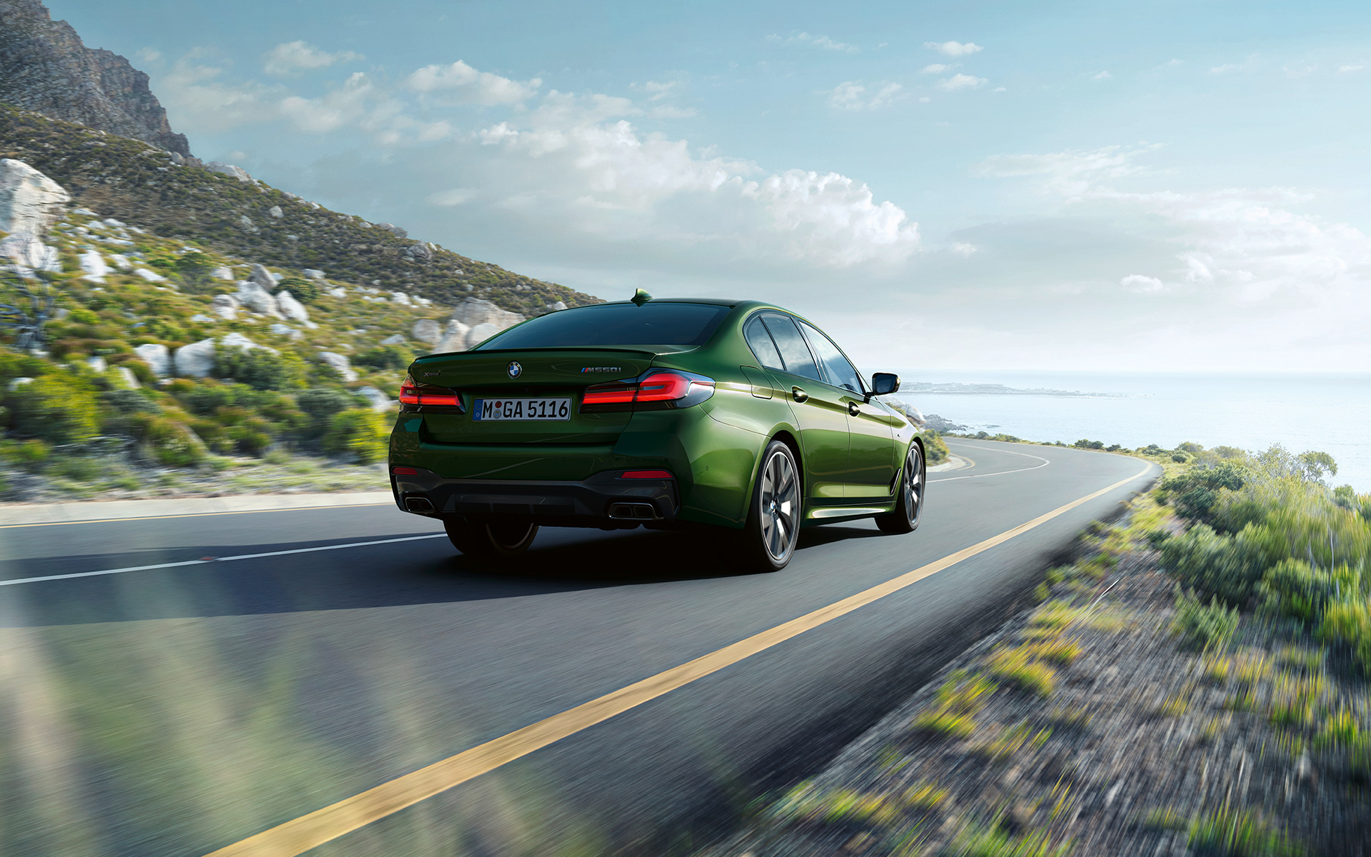 BMW M550i xDrive Sedan G30 LCI Facelift 2020 BMW Individual Verde Ermes 金屬外觀漆面行駛中的尾部四分之三之角度視圖