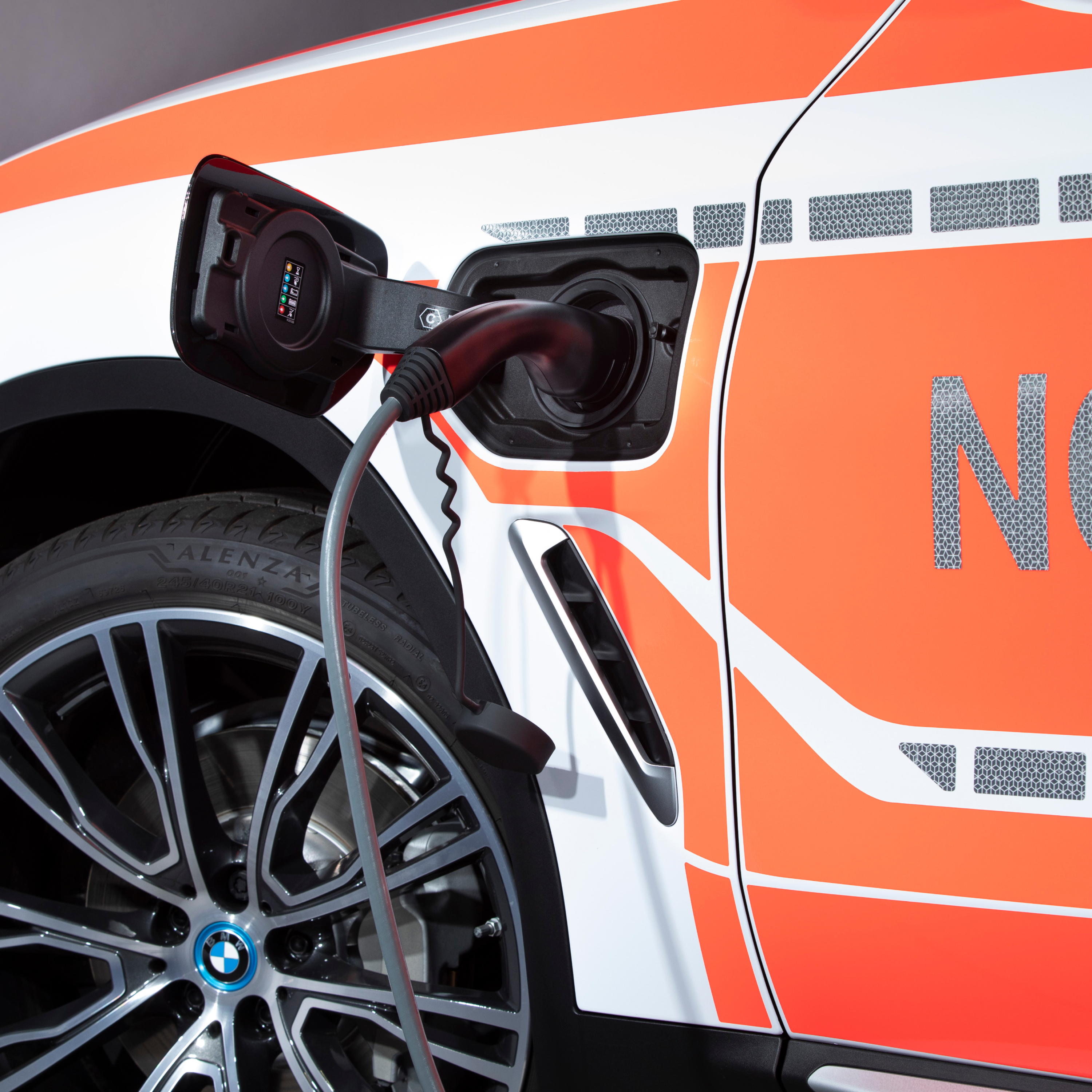 一輛 BMW 插電式混合動力公務車輛正在充電；充電電纜的特寫鏡頭